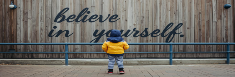 Child reading motivational wall message.